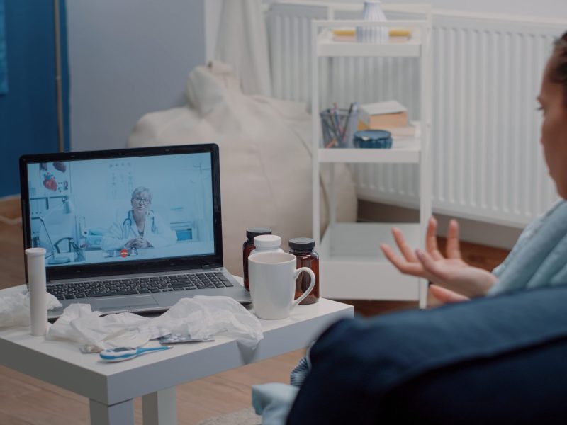 Patient with headache using video call for telemedicine and telehealth, asking doctor about treatment to cure pain and flu symptoms. Woman talking to specialist on online remote conference