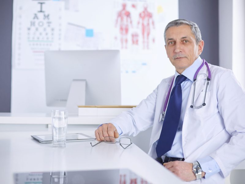 Portrait of senior doctor sitting in medical office.